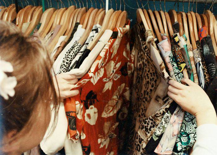 A woman looking through vintage clothes at a secondhand store.